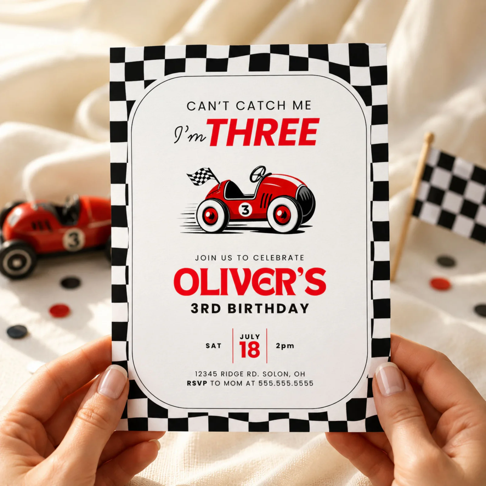 Race Car 3rd birthday invitation held in hands, featuring a vintage red race car and checkered flag.