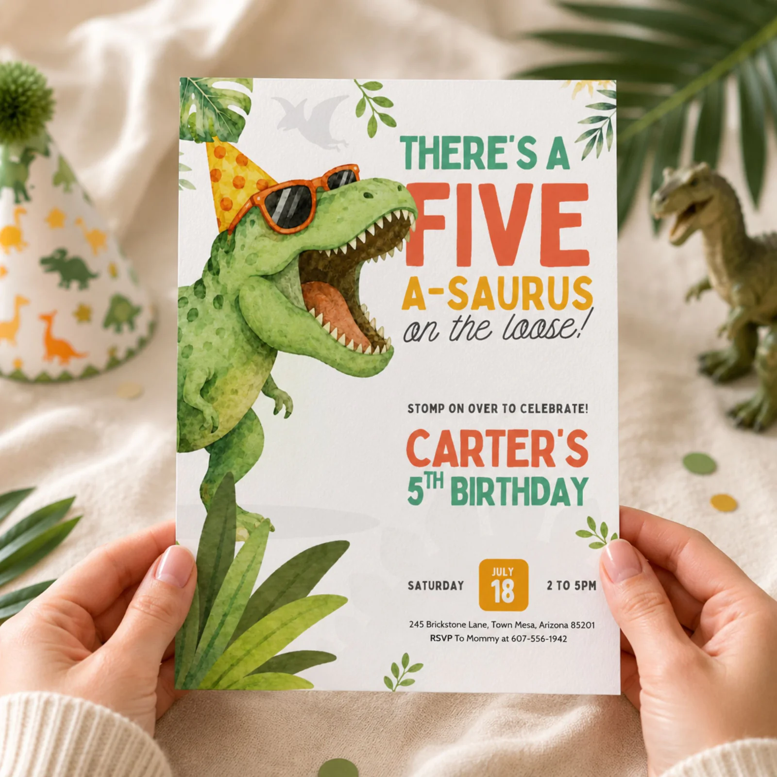 Dinosaur Birthday Invitation held in hands, featuring a green T-Rex with party hat and sunglasses, ready to send.