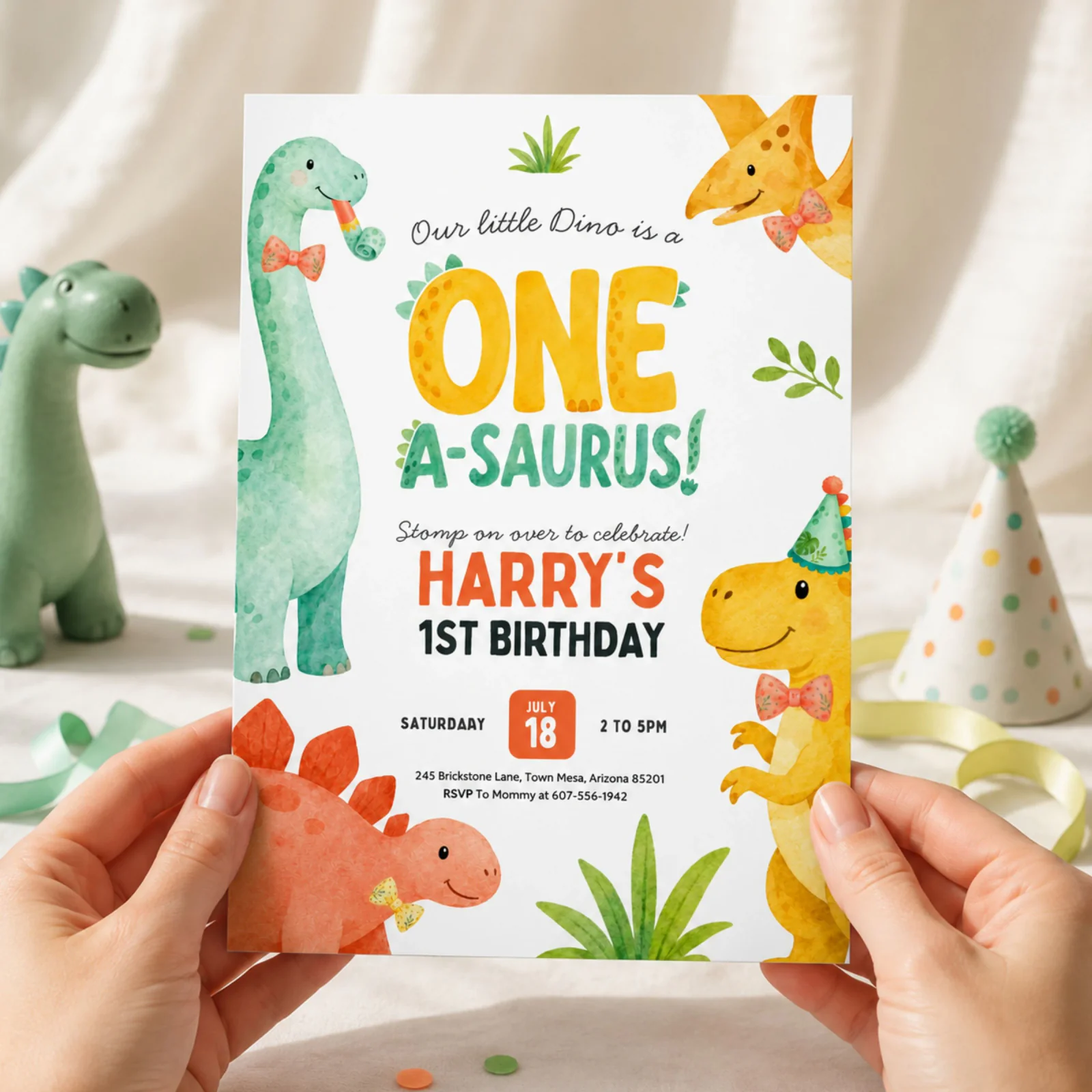 Dinosaur 1st birthday invitation held in hands, featuring the cute One A-Saurus design and party details.