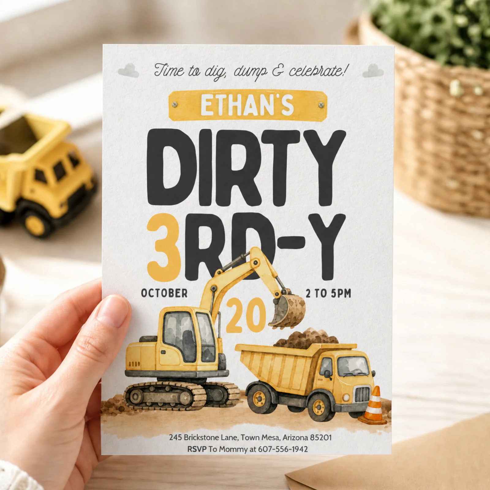Dirty 3rd-y birthday invitation held in hand, showcasing the construction dump truck design for a boy's party.