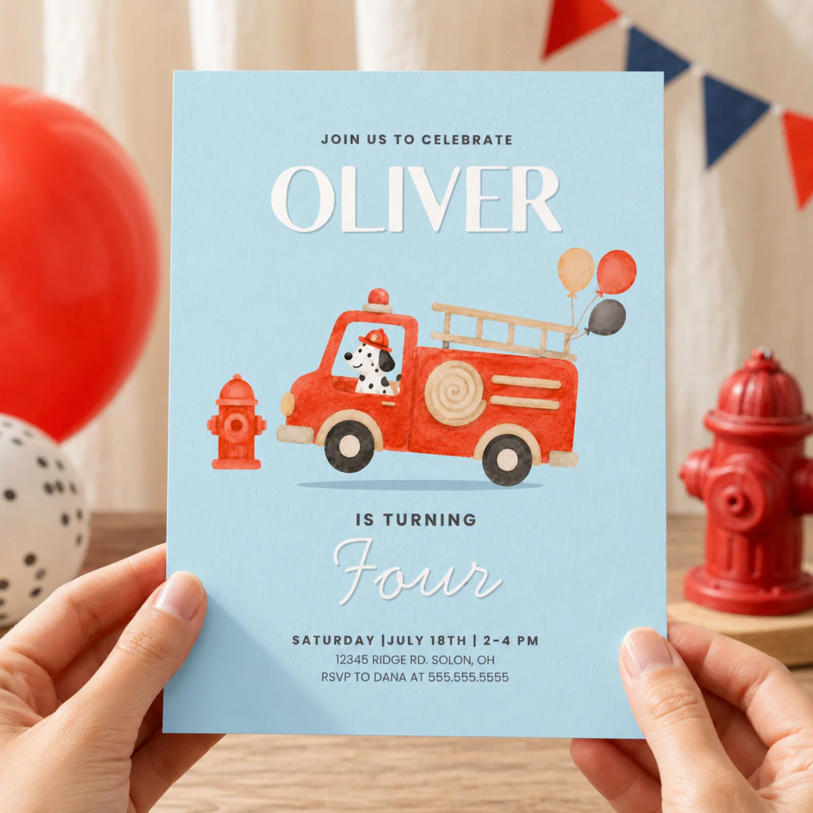 Fire truck birthday invitation held in hands, featuring a red fire engine and Dalmatian on a blue background.