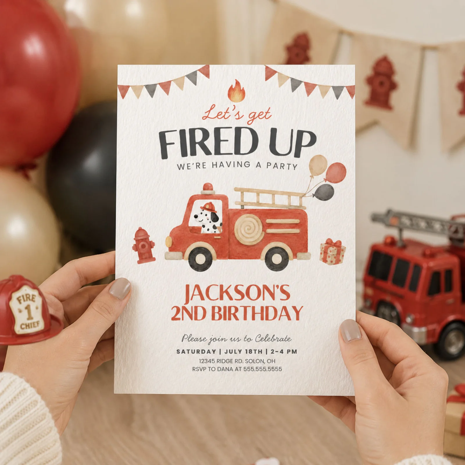 Fire Truck Birthday Invitation held in hands, featuring a red fire engine and Dalmatian puppy for a fire truck birthday party theme.
