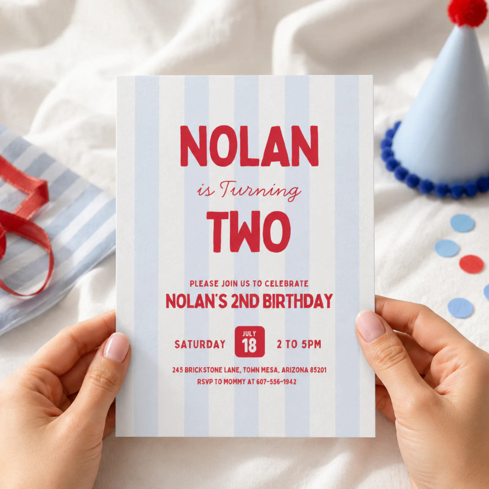 Striped birthday invitation held in hands, featuring a retro blue and white striped design for a boy's party.